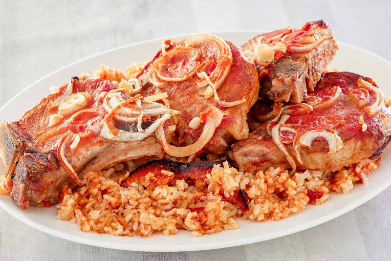 baked pork chops and rice with tomato sauce on a platter.