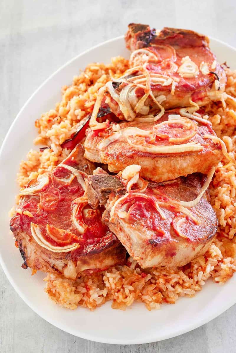 baked pork chops and rice on a white platter.