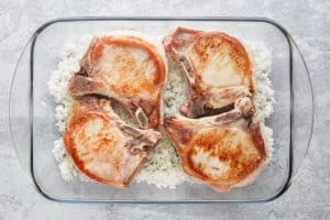 browned pork chops over rice in a baking dish.