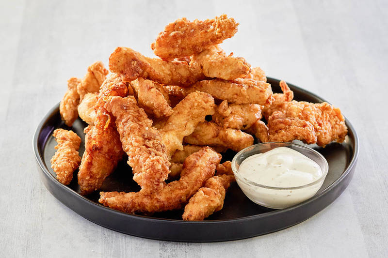 beer battered chicken strips and dipping sauce on a platter.