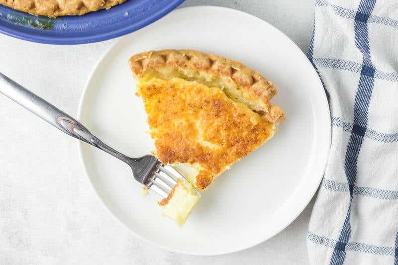 slice of old fashioned buttermilk pie and a fork on a plate.