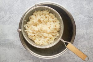 draining sauerkraut in a strainer over a bowl.