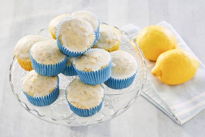 lemon poppy seed muffins on a stand and two lemons.