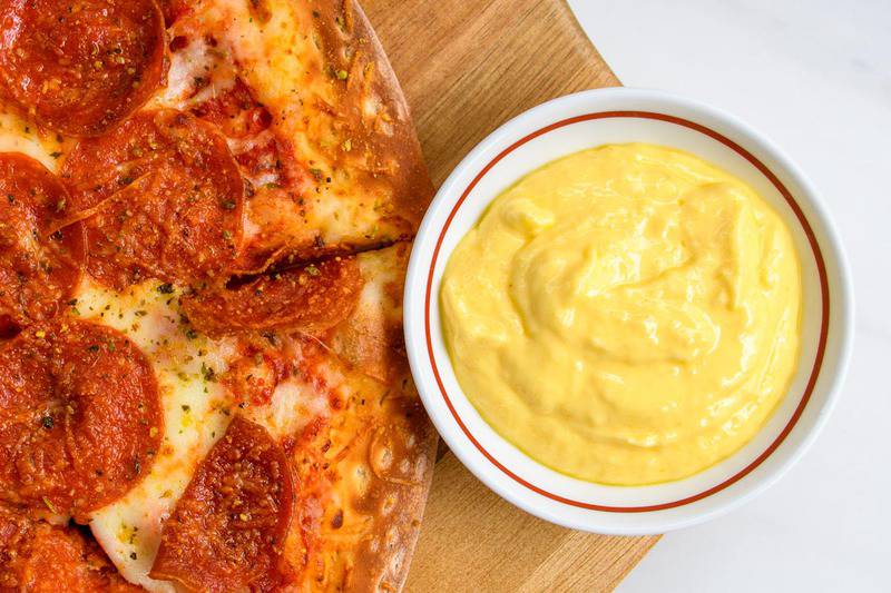 bowl of copycat Papa John's garlic sauce and a pepperoni pizza.