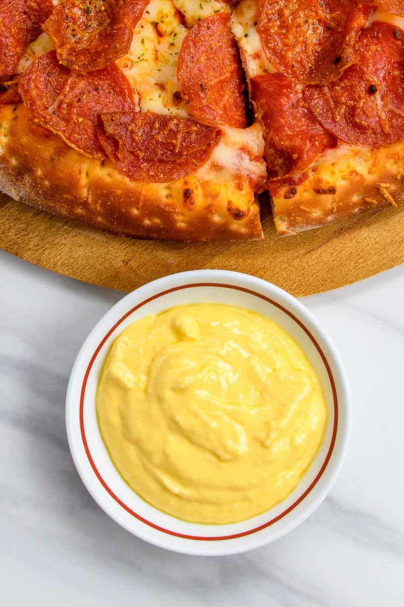 bowl of homemade Papa John's garlic sauce and a pizza.