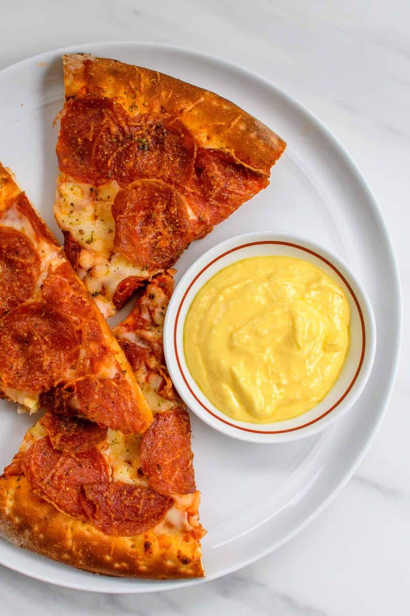 overhead view of copycat Papa John's garlic sauce and pizza on a plate.