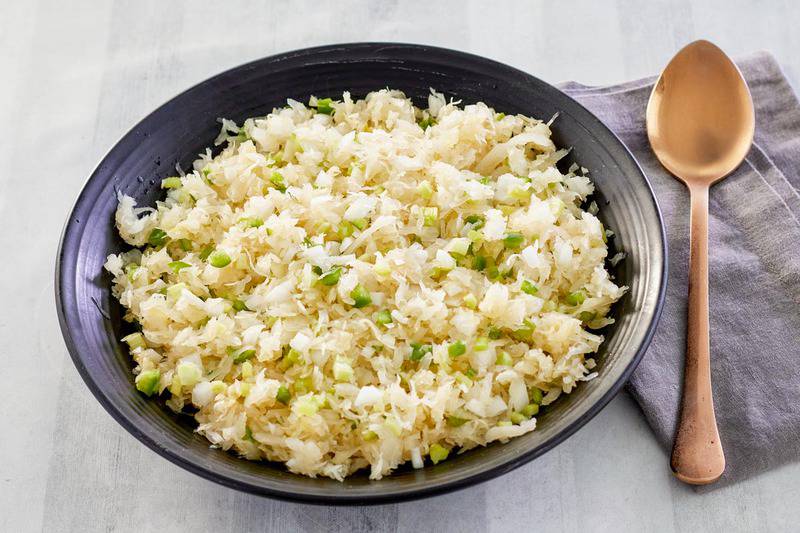 bowl of sauerkraut salad and a spoon on a cloth napkin.