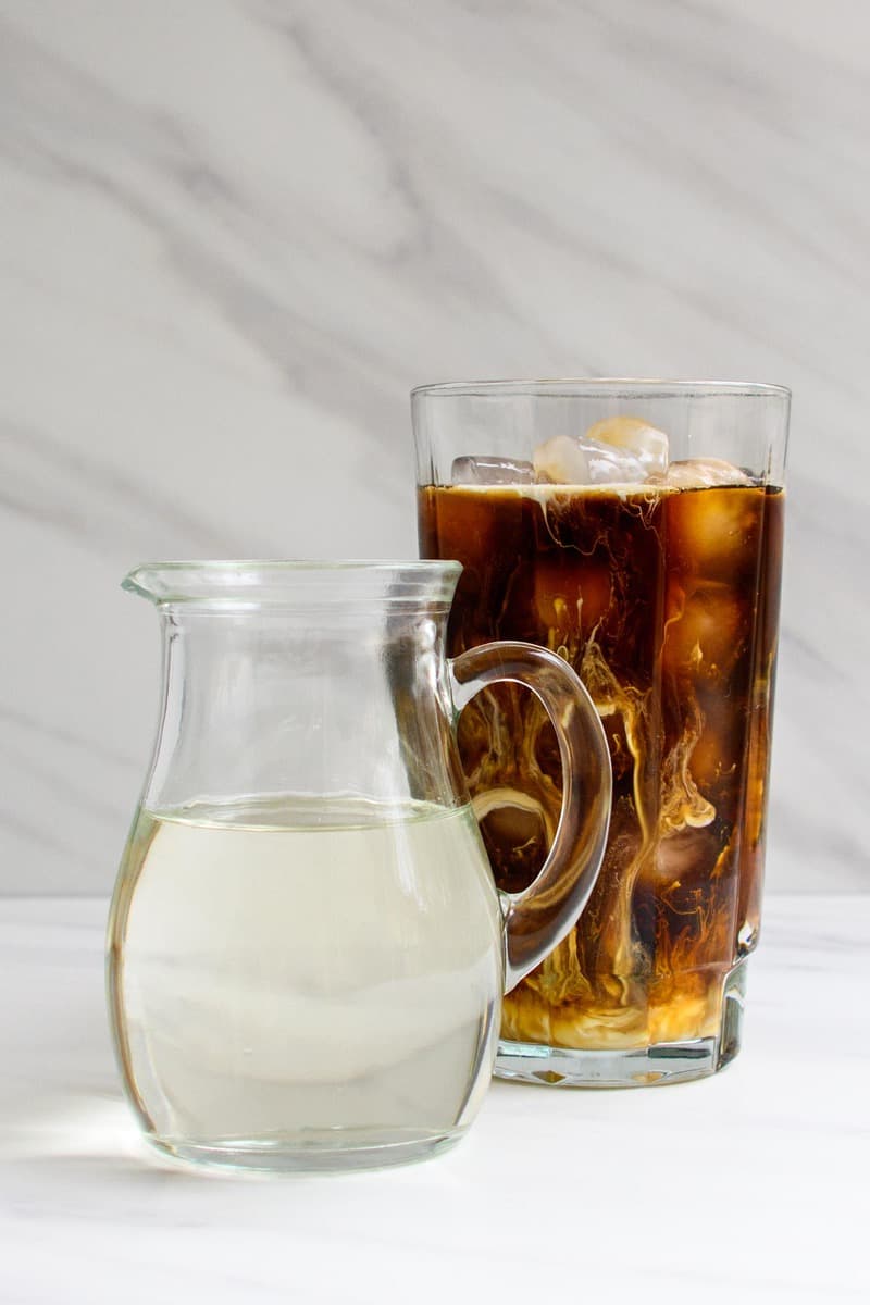 copycat Starbucks classic syrup in a small pitcher next to iced coffee.