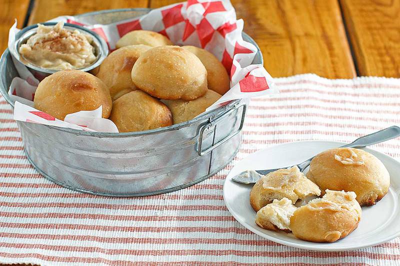 homemade Texas Roadhouse Rolls on a plate and in a metal serving tub.