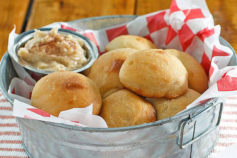 homemade Texas Roadhouse rolls and butter in a metal tub.