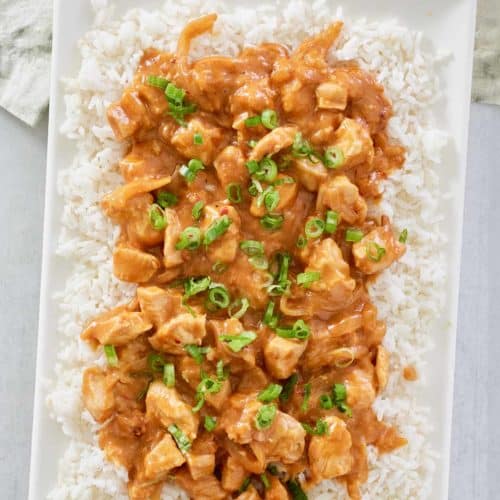 overhead view of Thai peanut chicken over rice on a platter.
