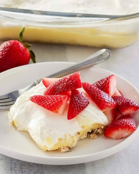 lemon lush topped with strawberries on a plate.