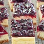 blueberry cheesecake bars with graham cracker crust in a row.