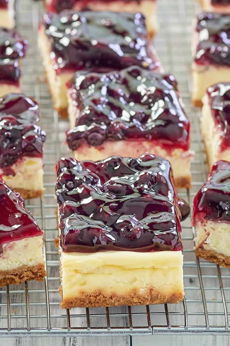 blueberry cheesecake bars with graham cracker crust in a row.