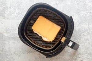 bread with cheese on top in an air fryer basket.