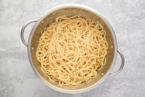 Bir kevgir içinde pişmiş spagetti erişte.