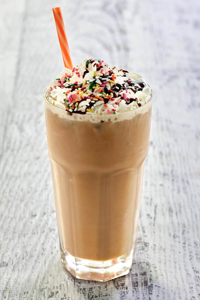 copycat Dunkin Donuts iced cake batter latte with chocolate drizzle and rainbow sprinkles.