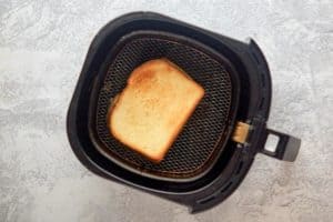 grilled cheese sandwich in an air fryer basket.