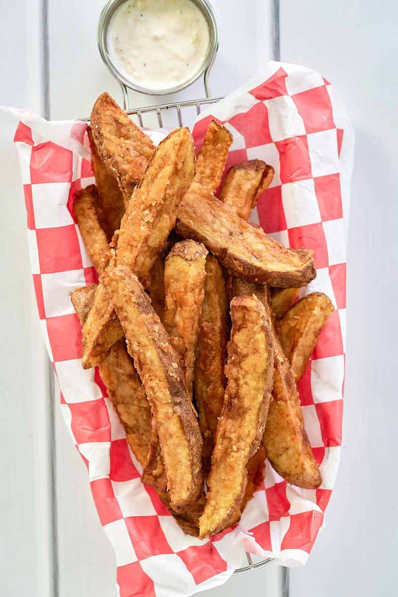 overhead view of homemade deep fried potato wedges and dipping sauce.