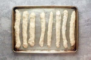Little Caesars crazy bread dough strips on a baking sheet.