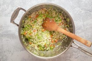 sautéing rice and vegetables in a pan.
