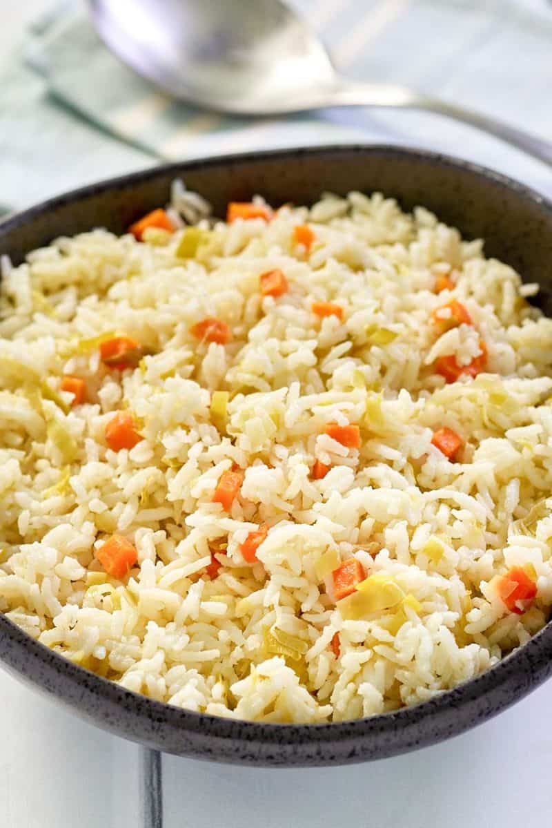 homemade rice pilaf in a black bowl and a spoon.