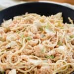 cold shrimp pasta salad in a trencher and wood salad tongs.