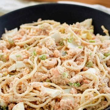 cold shrimp pasta salad in a bowl and wood salad tongs.