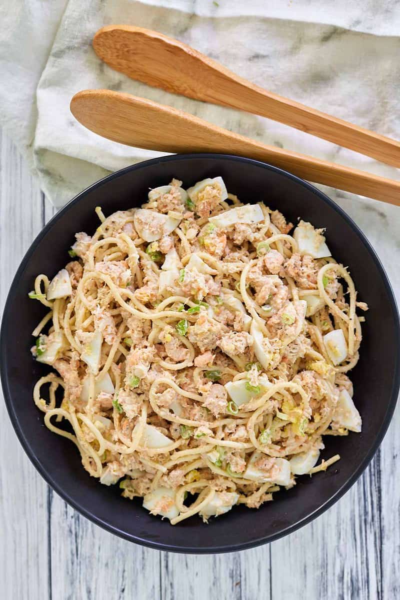 overhead view of shrimp pasta salad in a bowl and salad tongs.