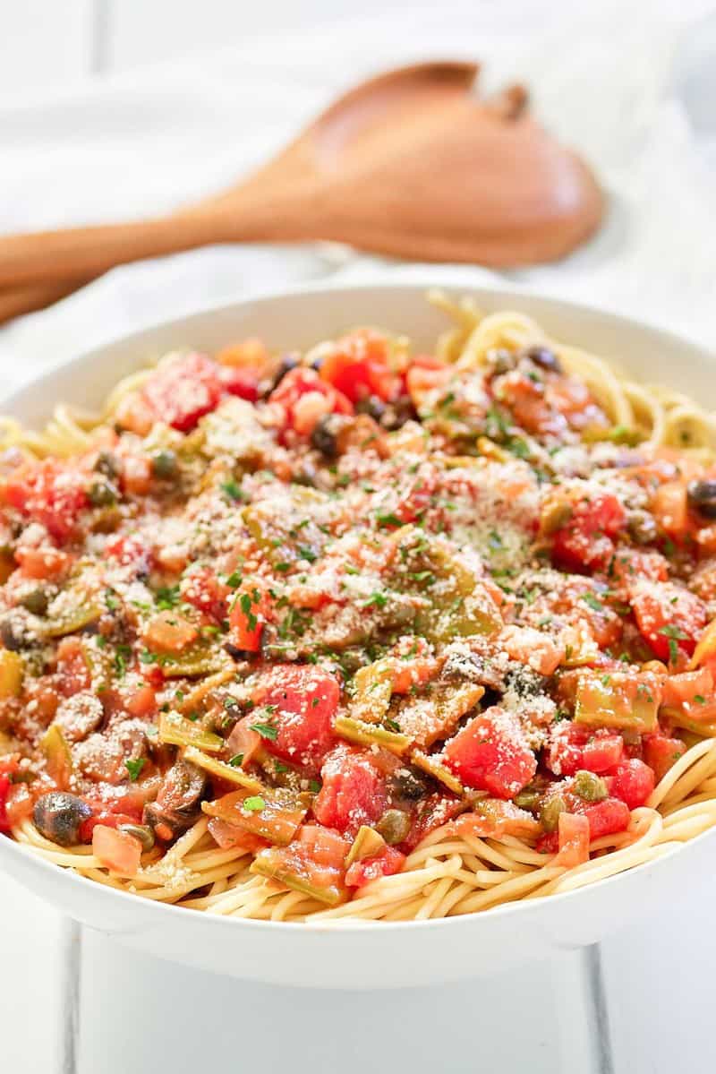 spaghetti alla puttanesca and wood serving spoons.