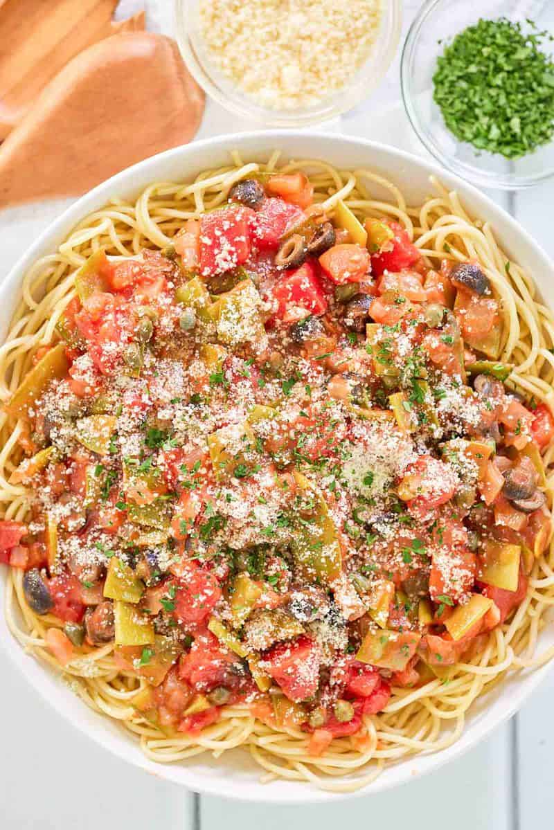 spagetti alla puttanesca, parmesan peyniri ve kıyılmış maydanozun havai görünümü.