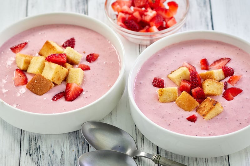 two bowls of strawberry soup with fresh strawberries and pound cake croutons.