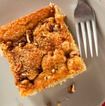 slice of cinnamon pudding cake and a fork on a plate.