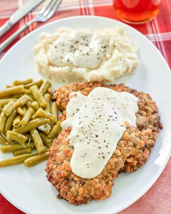 copycat Cracker Barrel country fried steak, gravy, and sides on a plate.