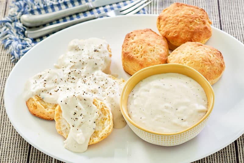 copycat Cracker Barrel sawmill gravy in a bowl and pver biscuits.