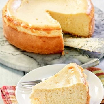 copycat Lindy's New York Cheesecake on a platter and a slice in front of it.