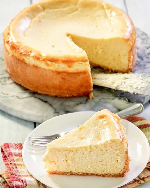 copycat Lindy's New York Cheesecake on a platter and a slice in front of it.