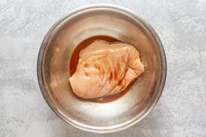 chicken breast marinating in a bowl with cornstarch, sherry, soy sauce, and water.