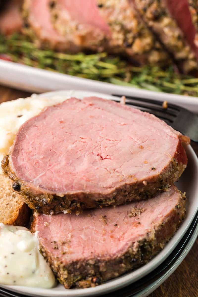 two smoked eye of round roast slices on a plate.