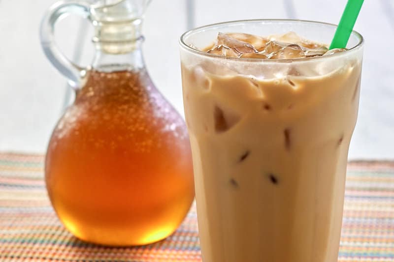 copycat Starbucks vanilla syrup in a small pitcher and an iced coffee drink.