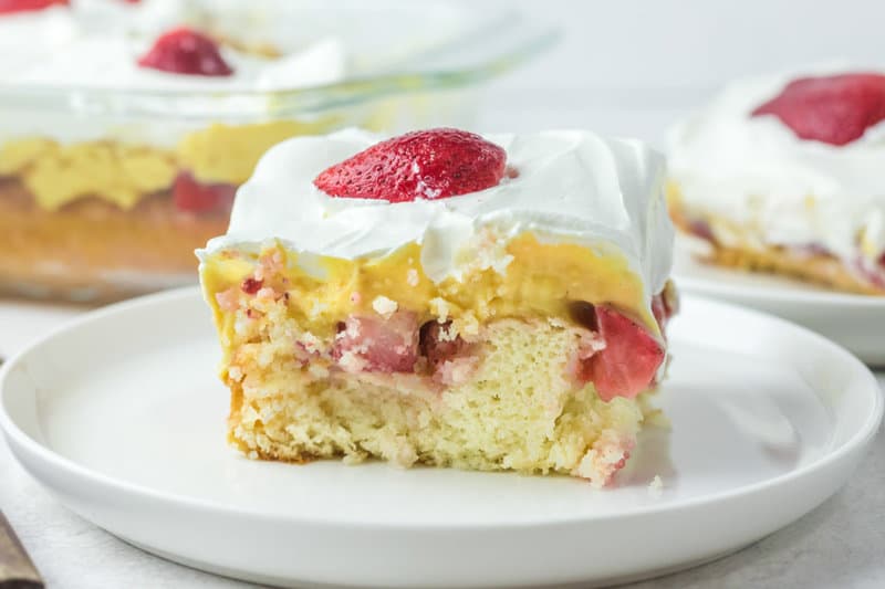 strawberry poke cake slice on a plate in front of the cake.