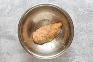 seasoned raw chicken breast in a bowl.