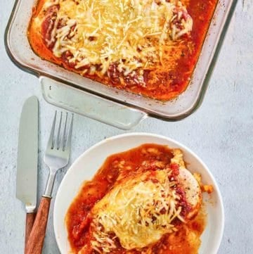 overhead view of baked chicken parmesan on a plate and in a baking dish.