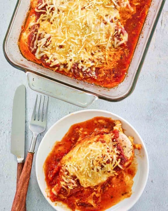 overhead view of baked chicken parmesan on a plate and in a baking dish.