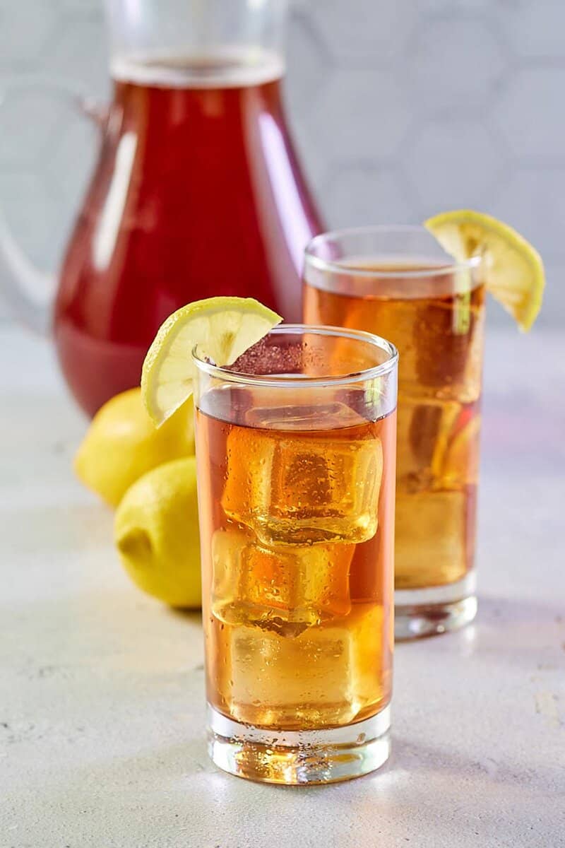 copycat chick fil a sweet tea in a pitcher and two glasses with ice.