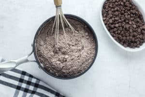 whisking chocolate cake mix into chocolate pudding.