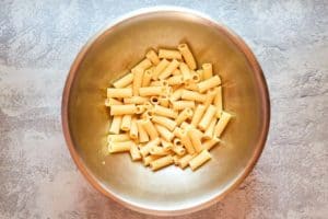 cooked rigatoni pasta in a stainless steel bowl.