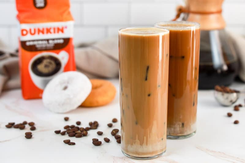 two copycat Dunkin Donuts butter pecan iced coffee drinks, a bag of Dunkin coffee grounds, and two donuts.