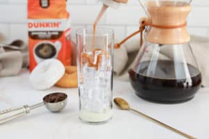 adding butter pecan swirl flavoring to a glass with ice.