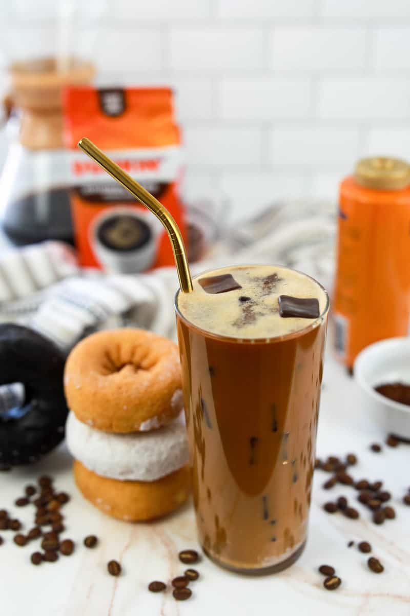 copycat dunkin donuts caramel iced coffee and three donuts next to it.